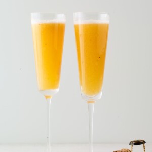 Two champagne flutes containing an easy peach Bellini.