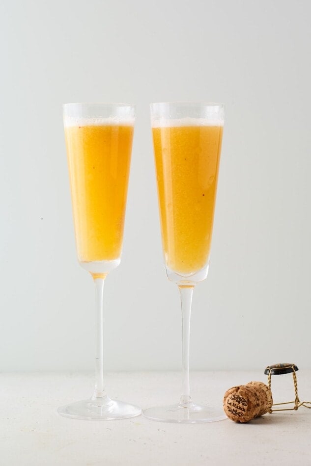 Two champagne flutes containing an easy peach Bellini.