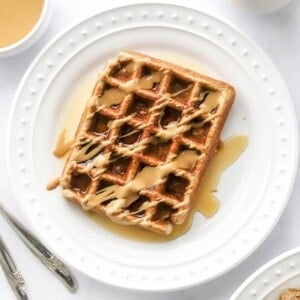 An overhead photo looking at a plate with a rectangular protein waffle that has been drizzled with maple syrup and peanut butter.