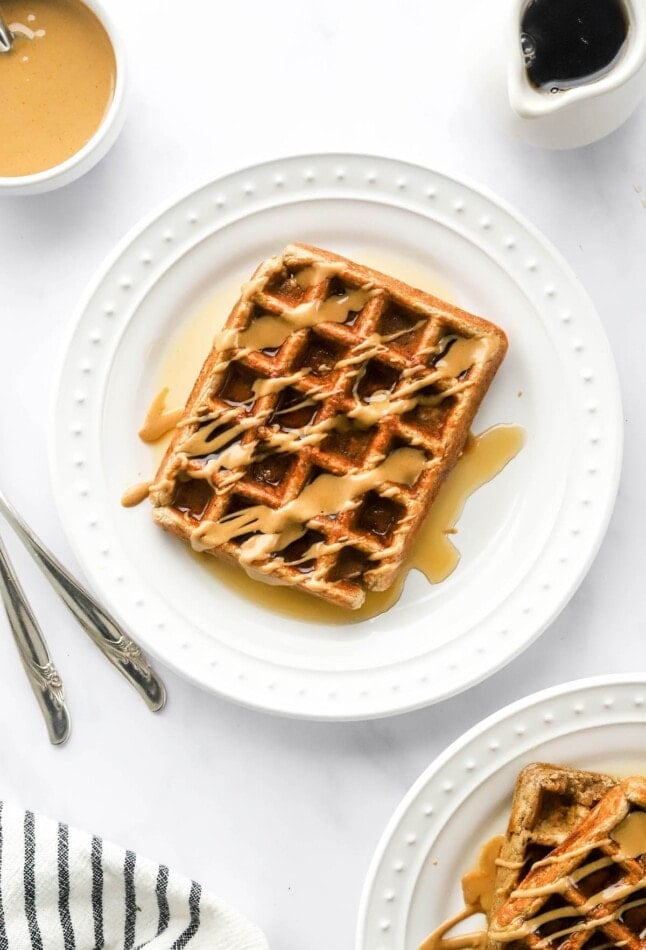 An overhead photo looking at a plate with a rectangular protein waffle that has been drizzled with maple syrup and peanut butter.