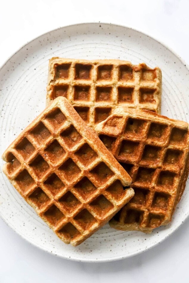 A stack of waffles on a plate.