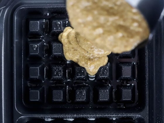 Pouring the waffle batter onto a waffle iron.