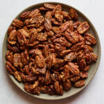 A shallow serving dish containing candied pecans.