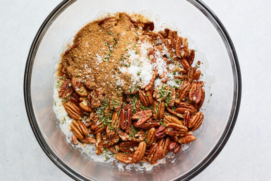 Pecans, sugar, rosemary, and salt added to a large bowl containing whipped egg whites.