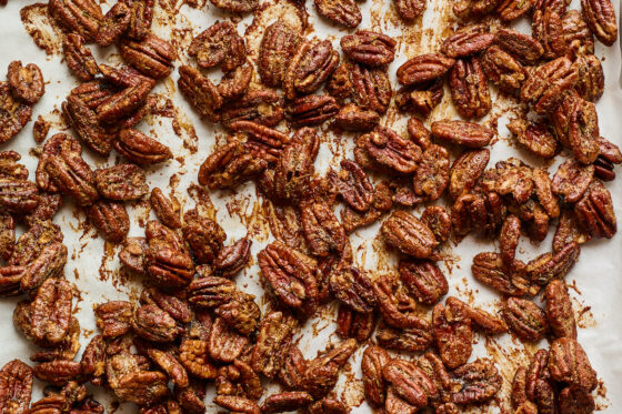 Candied pecans on a parchment lined baking sheet after baking.