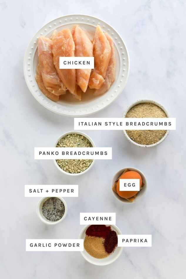 Ingredients measured out to make chicken tenders: chicken breast strips, Italian breadcrumbs, panko, egg, salt, pepper, cayenne, paprika and garlic powder.