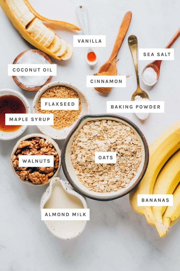 Ingredients measured out to make banana bread baked oatmeal: vanilla, cinnamon, salt, baking powder, coconut oil, flaxseed, maple syrup, oats, walnuts, almond milk and bananas.