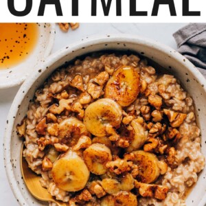 A bowl containing banana bread oatmeal that has been topped with caramelized bananas and walnuts. A spoon rests in the bowl.