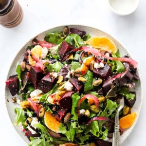 An overhead photo of a plate containing baby beet and clementine salad. A fork rests on the plate.
