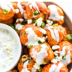 Bowl fo buffalo chicken meatballs topped with ranch, blue cheese and green onions.