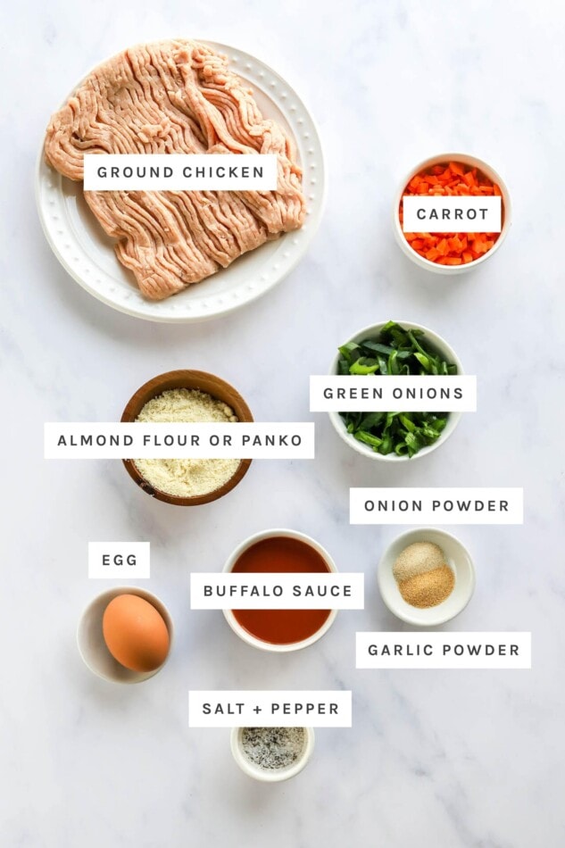 Ingredients measured out to make buffalo chicken meatballs: ground chicken, carrot, almond flour, green onions, onion powder, garlic powder, buffalo sauce, egg, salt and pepper.