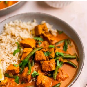 A bowl containing butter chicken on one side and rice on the other.