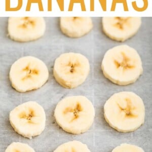 Slices of frozen banana on a parchment-lined cookie sheet.