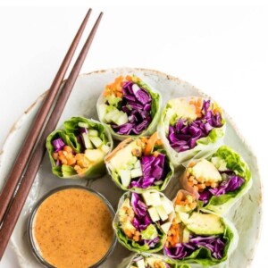 Plate of vegetable spring fresh rolls with chopsticks and a side bowl of peanut dipping sauce.