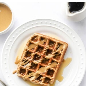 An overhead photo looking at a plate with a rectangular protein waffle that has been drizzled with maple syrup and peanut butter.