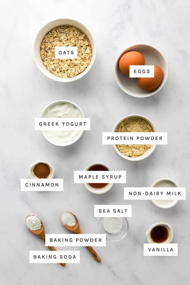 Ingredients measured out to make protein waffles: oats, eggs, Greek yogurt, protein powder, cinnamon, maple syrup, non-dairy milk, sea salt, baking powder, baking soda and vanilla.