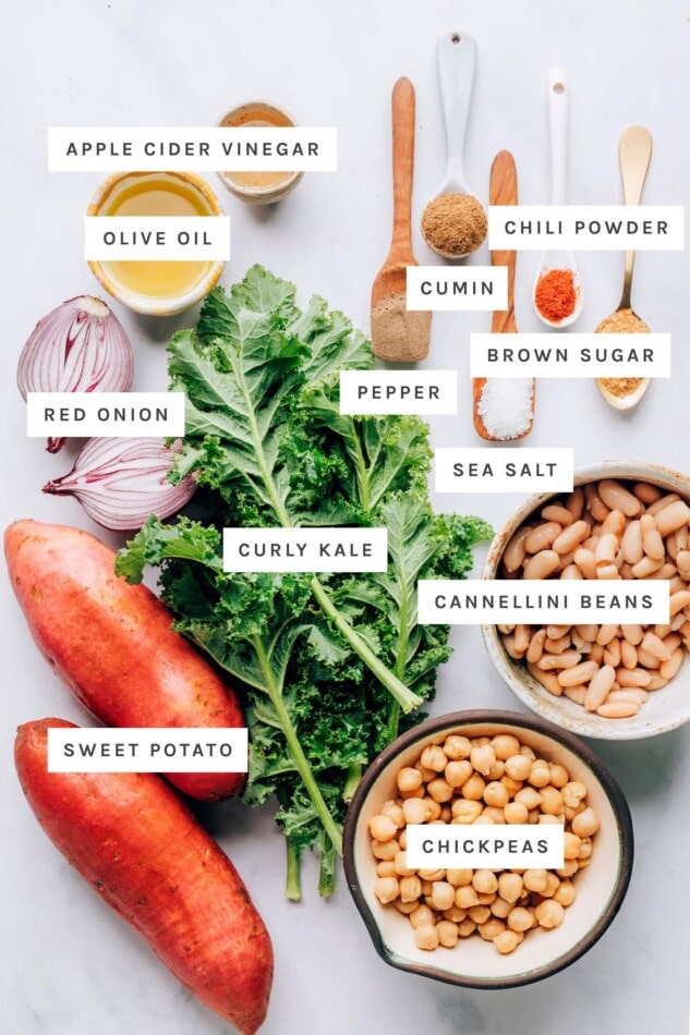 Ingredients measured out to make vegan power bowls: apple cider vinegar, pepper, cumin, chili powder, brown sugar, sea salt, olive oil, red onion, curly kale, cannellini beans, sweet potato and chickpeas.