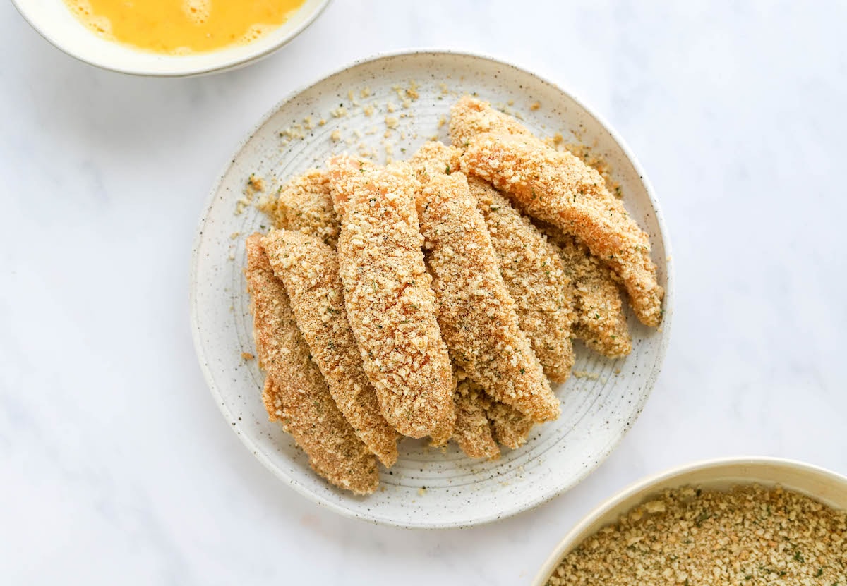 Dredged chicken tenders on a plate.