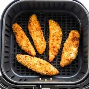 5 air fried chicken tenders in an air fryer basket.