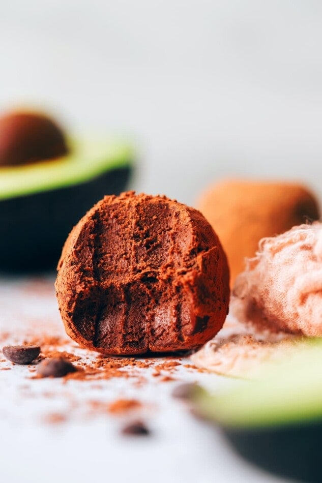 An avocado truffle with a bite taken out of it.