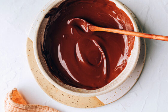 Chocolate melted in a bowl. A wooden spoon rests in the bowl.