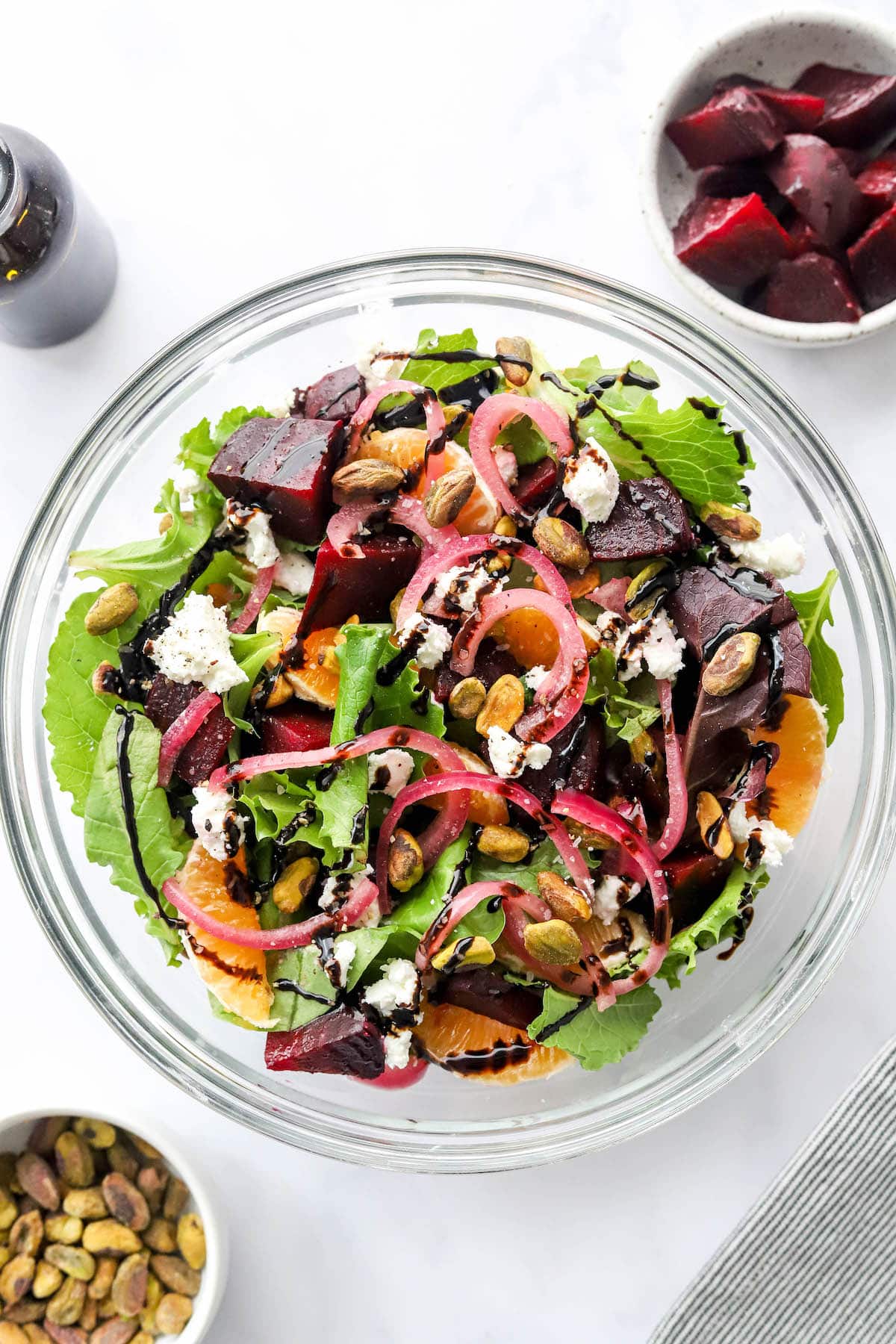 A birds eye view of a glass bowl containing a baby beet and clementine salad.