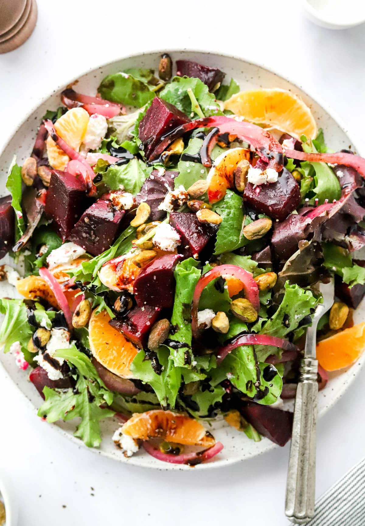 An overhead photo of a plate containing baby beet and clementine salad. A fork rests on the plate.