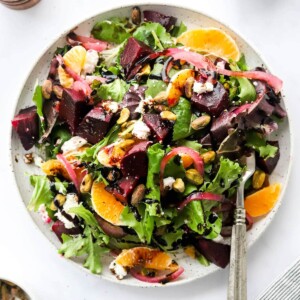 An overhead photo of a plate containing baby beet and clementine salad. A fork rests on the plate.