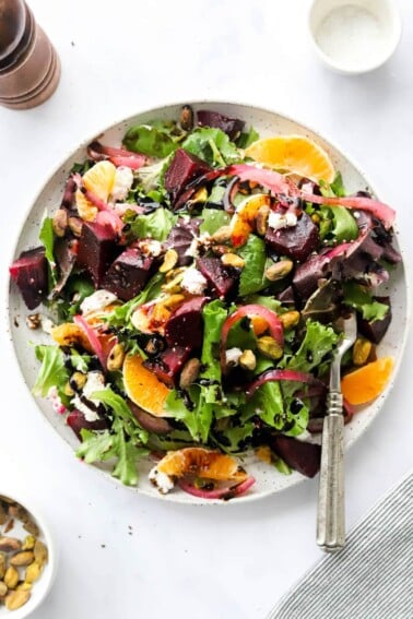 An overhead photo of a plate containing baby beet and clementine salad. A fork rests on the plate.
