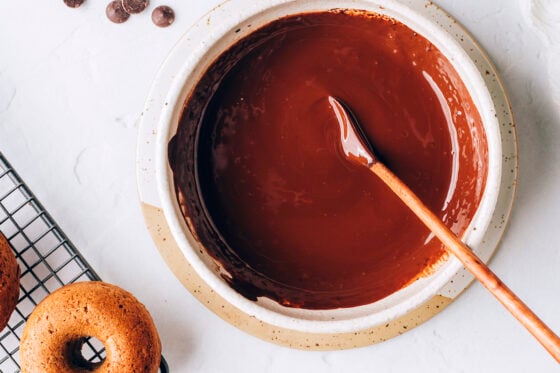 A bowl with chocolate dipping sauce. A wooden spoon lays in the bowl.