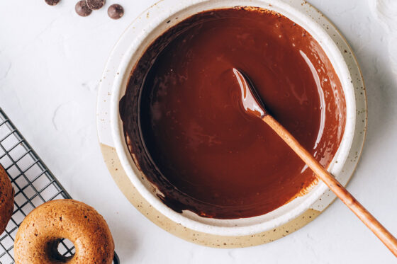 A bowl with chocolate dipping sauce. A wooden spoon lays in the bowl.