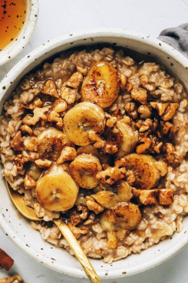 An overhead photo of a bowl of banana bread oatmeal, topped with banana slices and walnuts, and drizzled with maple syrup.