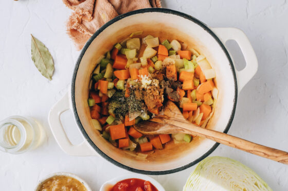Garlic, thyme, cinnamon, bay leaf, salt and pepper added to the vegetables in a large pot.
