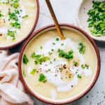 A bowl of cauliflower soup topped with fresh herbs.