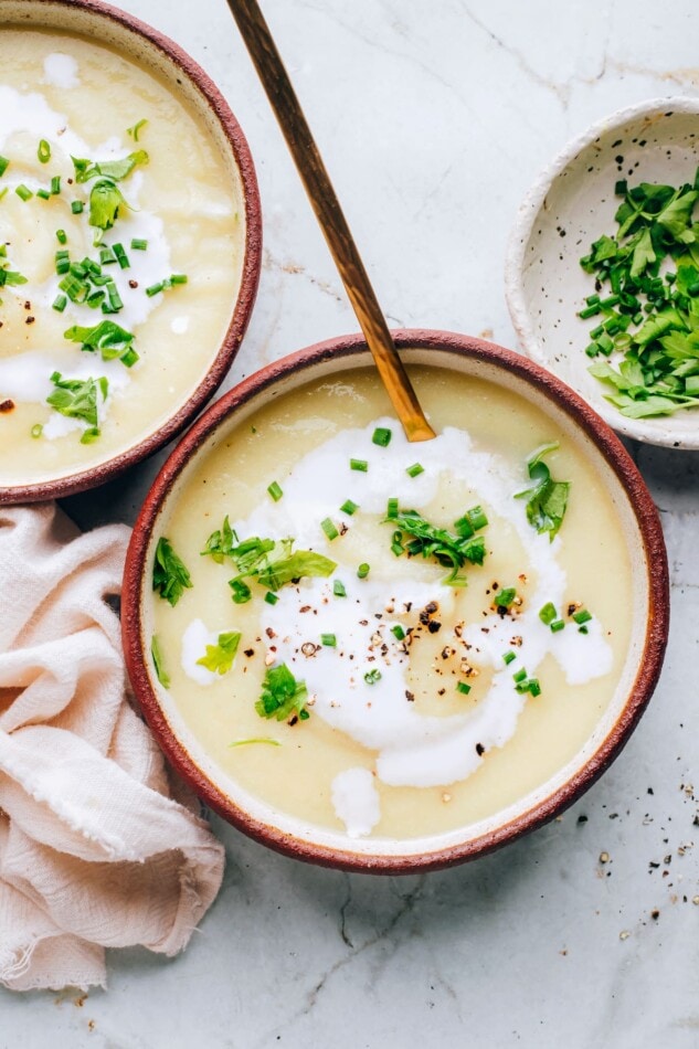 A bowl of cauliflower soup topped with fresh herbs.