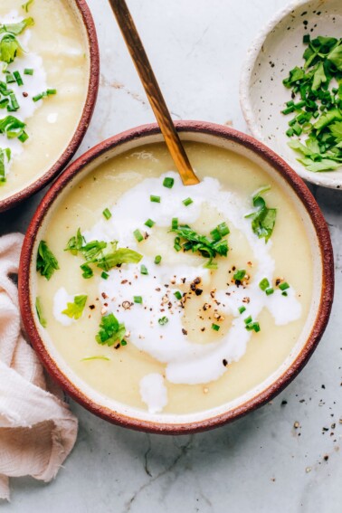 A bowl of cauliflower soup topped with fresh herbs.