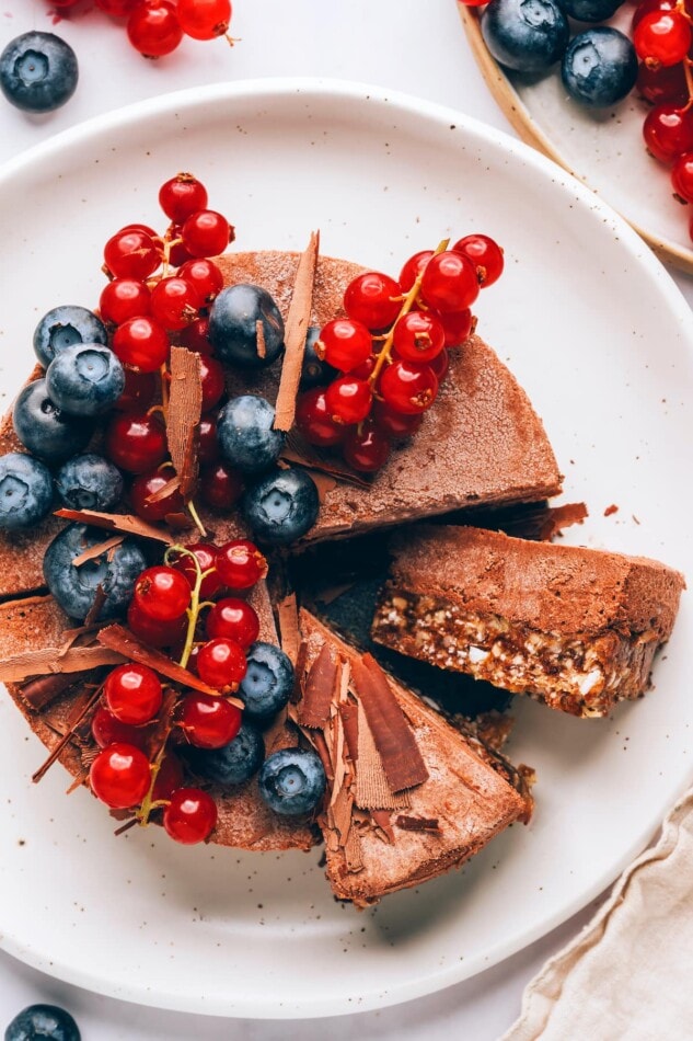 A plated vegan chocolate tart. The tart has been sliced and one of them is on its side so you can see the two layers.