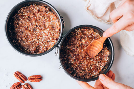 Two mini spring form pans with the coconut, pecan and date mixture pressed into the bottom.