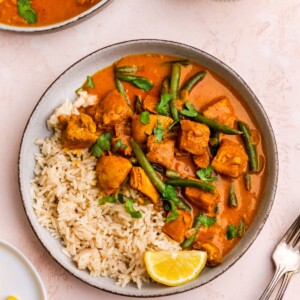 A birds eye view of a bowl containing half rice and half butter chicken.