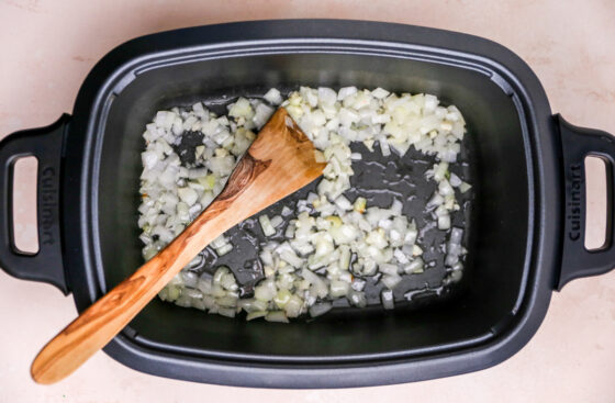 Garlic and onion sautéing in oil in the bottom of a slow cooker.