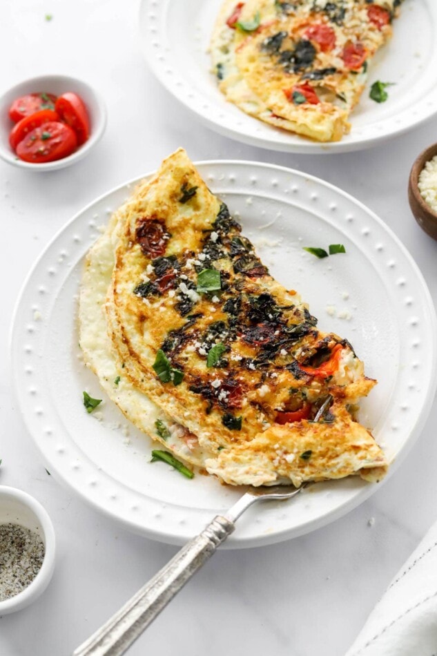 An egg white omelette on a white plate, a fork rests on the plate.