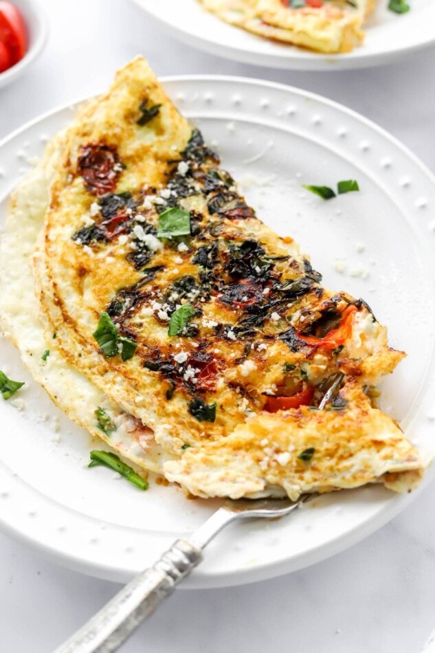 An egg white omelette on a plate, a fork is removing a bite.
