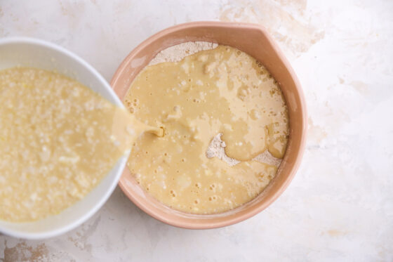 Wet ingredients being poured into a mixing bowl with dry ingredients.