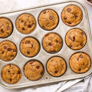 Twelve chocolate chip muffins in a muffin tin.