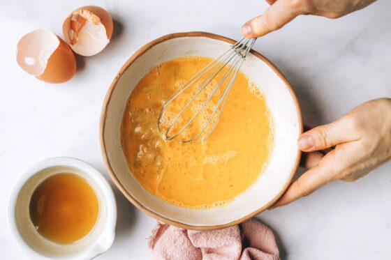 Eggs being whisked together with maple syrup, apple sauce, milk, oil, and vanilla.