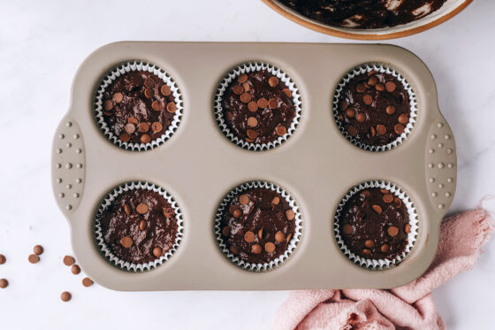 The batter has been poured into the lined muffin tin.