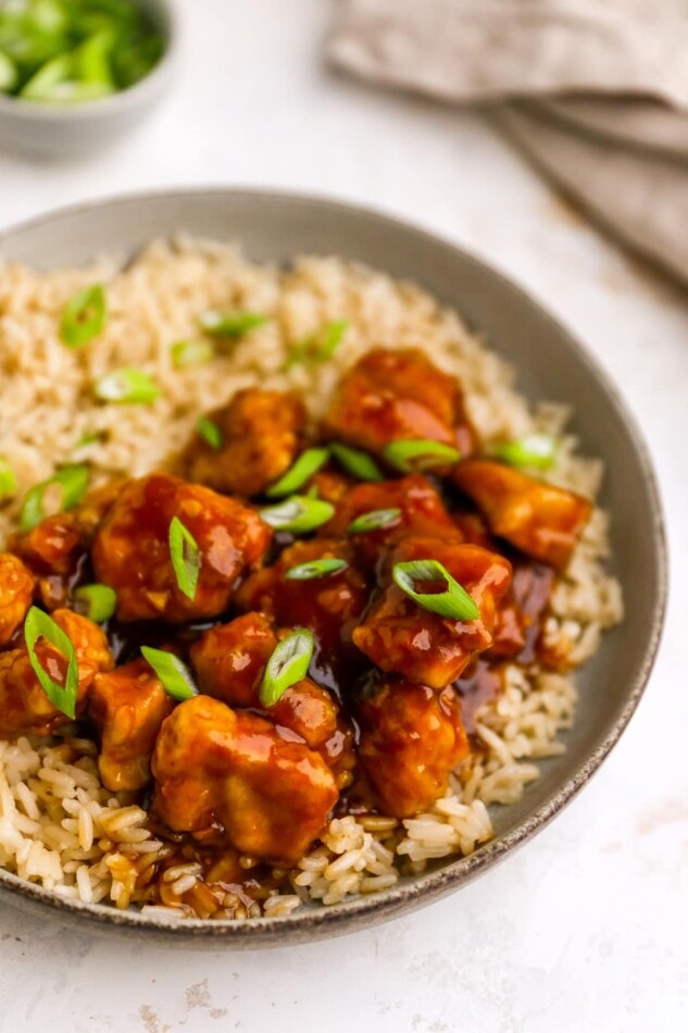 A closeup of healthy orange chicken served over a bed rice.