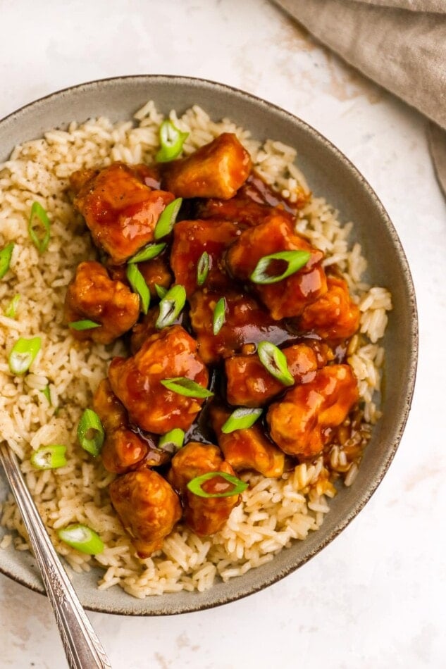 A closeup overhead photo of healthy orange chicken served over a bed of rice.