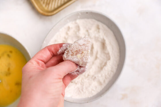 Coating chicken in flour after the egg wash.