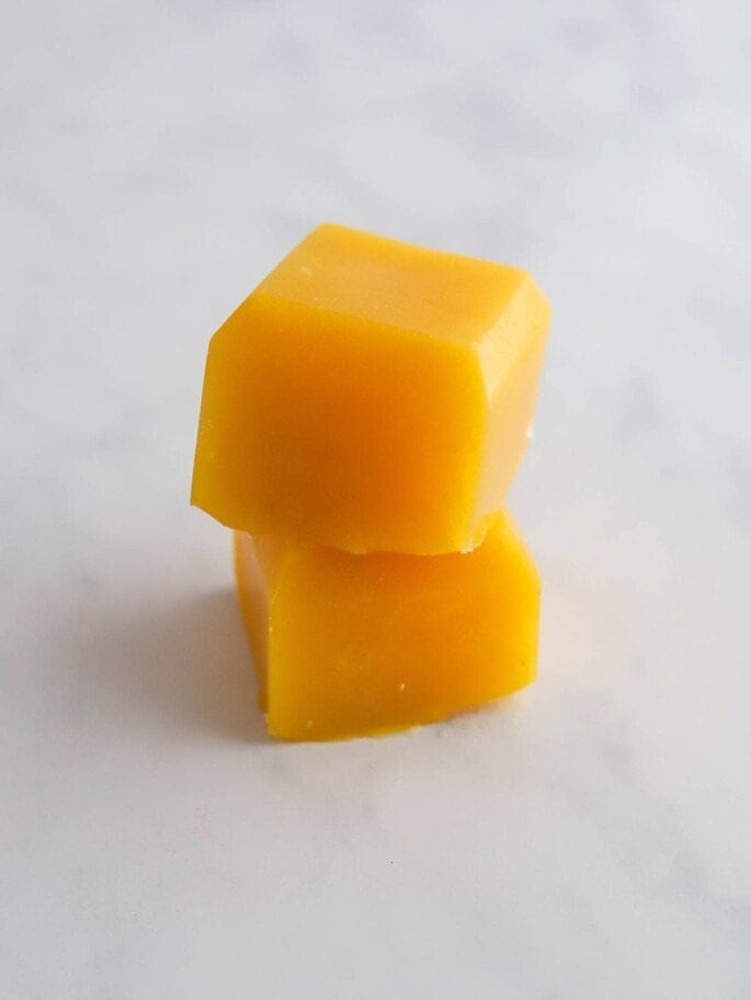 Two cubes of frozen mango puree stacked on top of each other.